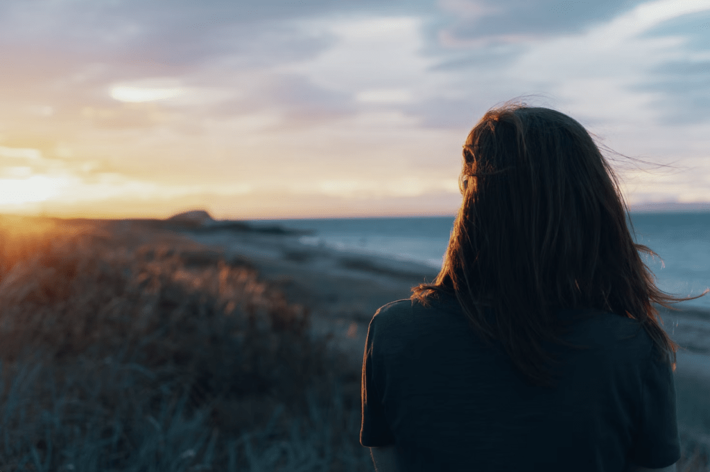 A woman enjoying a beautiful sunset on a beach in North Berwick, UK