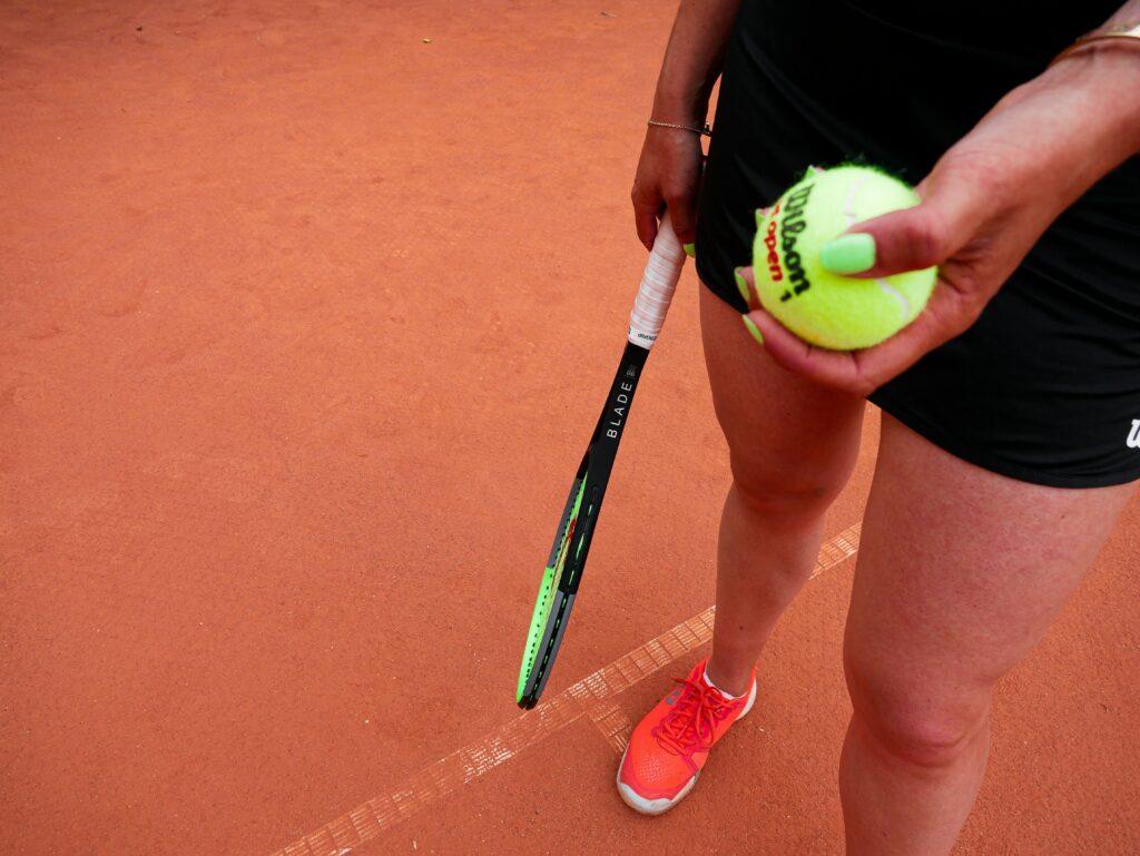 A clay court and a woman wearing red tennis shoes
